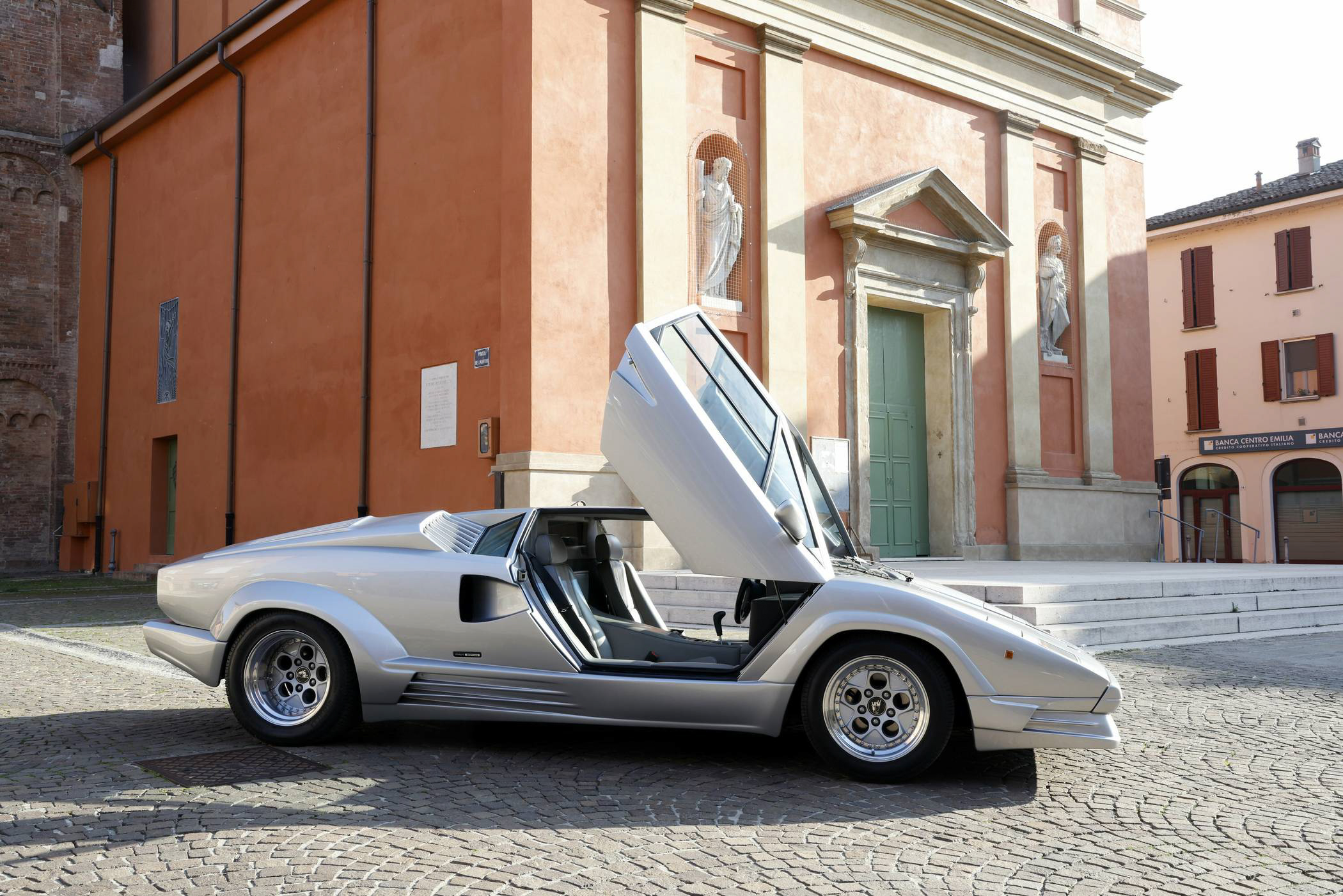 Silver Lamborghini Countach with doors open in Italian piazza